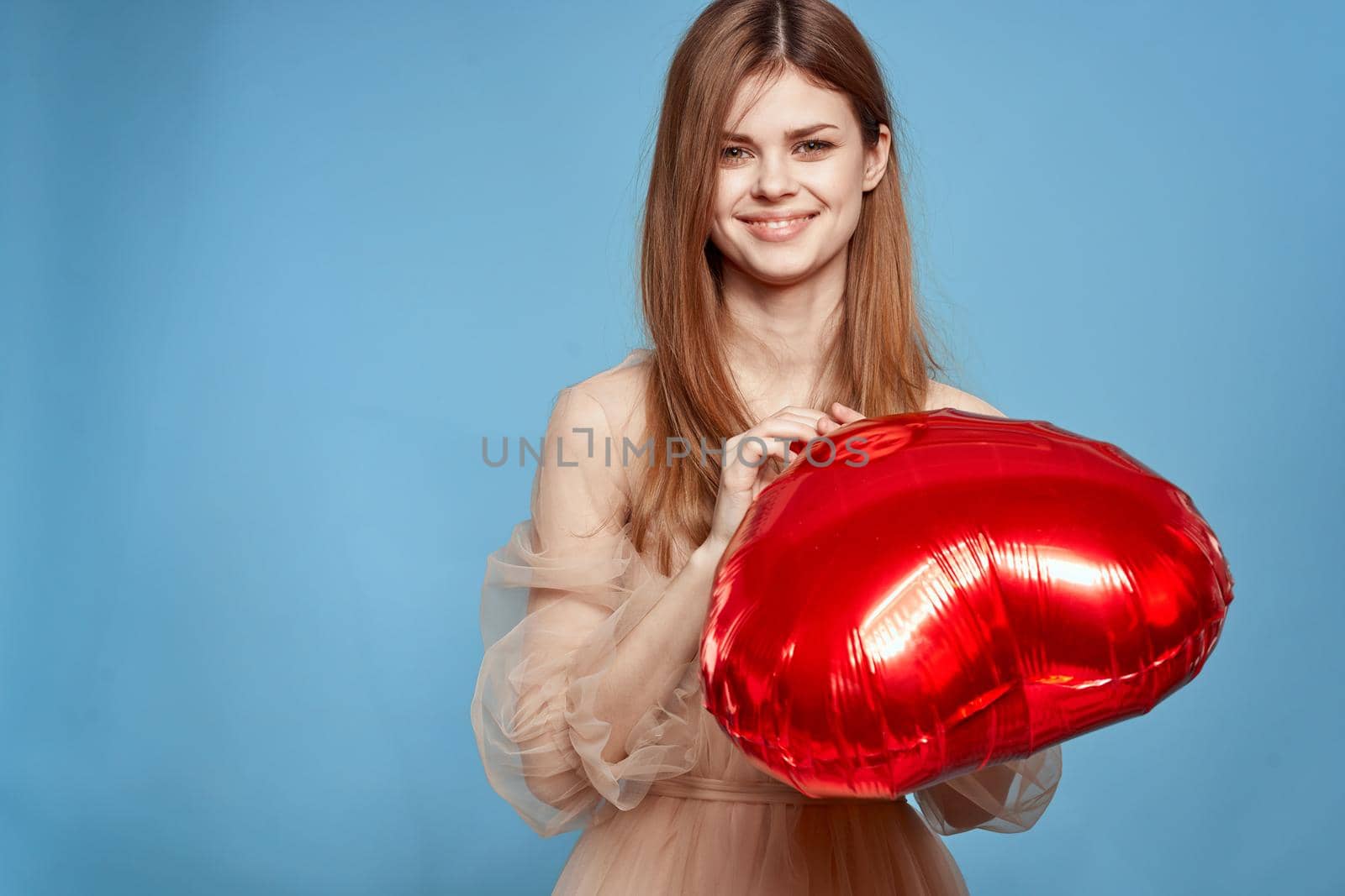 portrait of a woman red heart in the hands of the balloon blue background. High quality photo