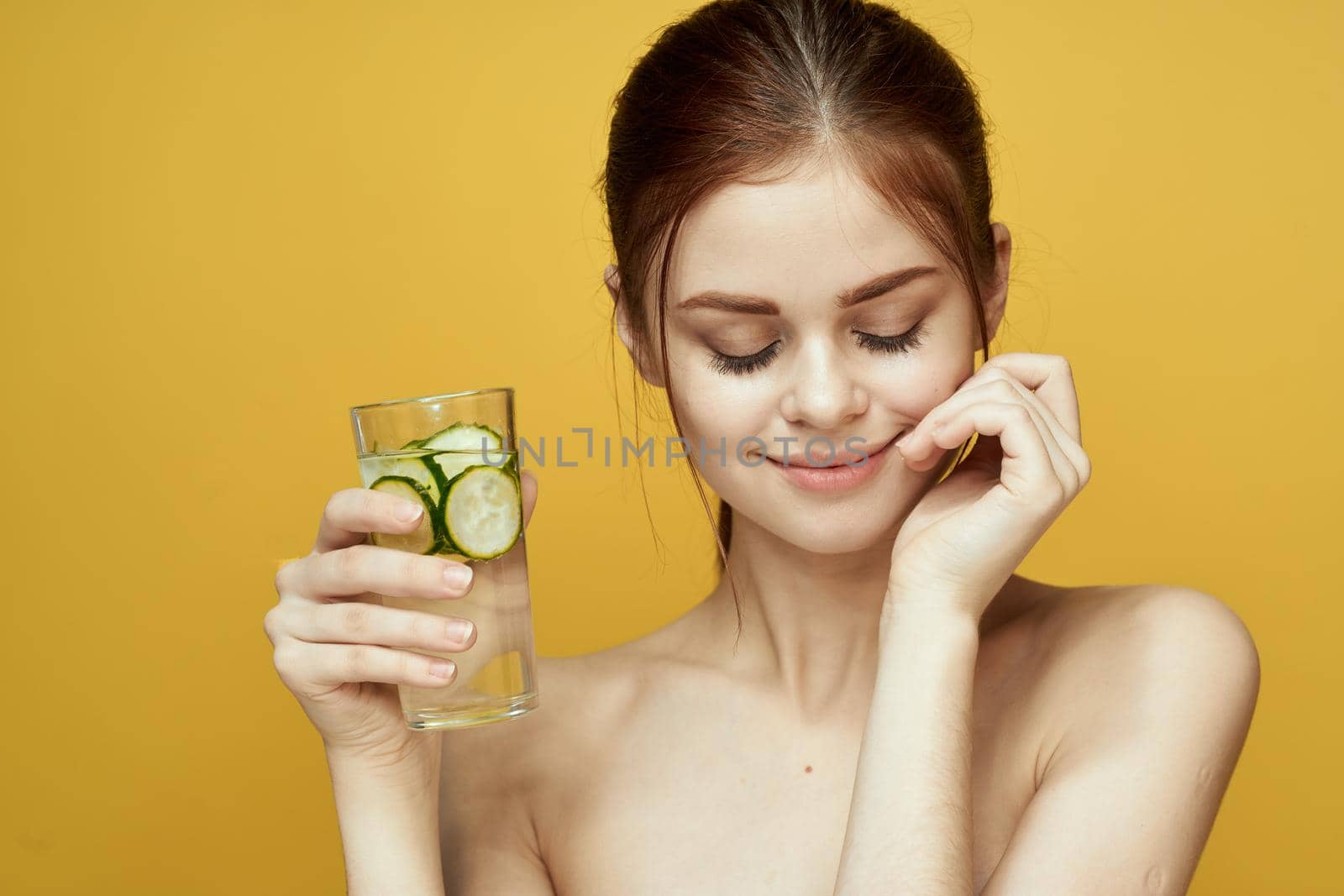 woman with cucumber drink vitamins body care yellow background. High quality photo