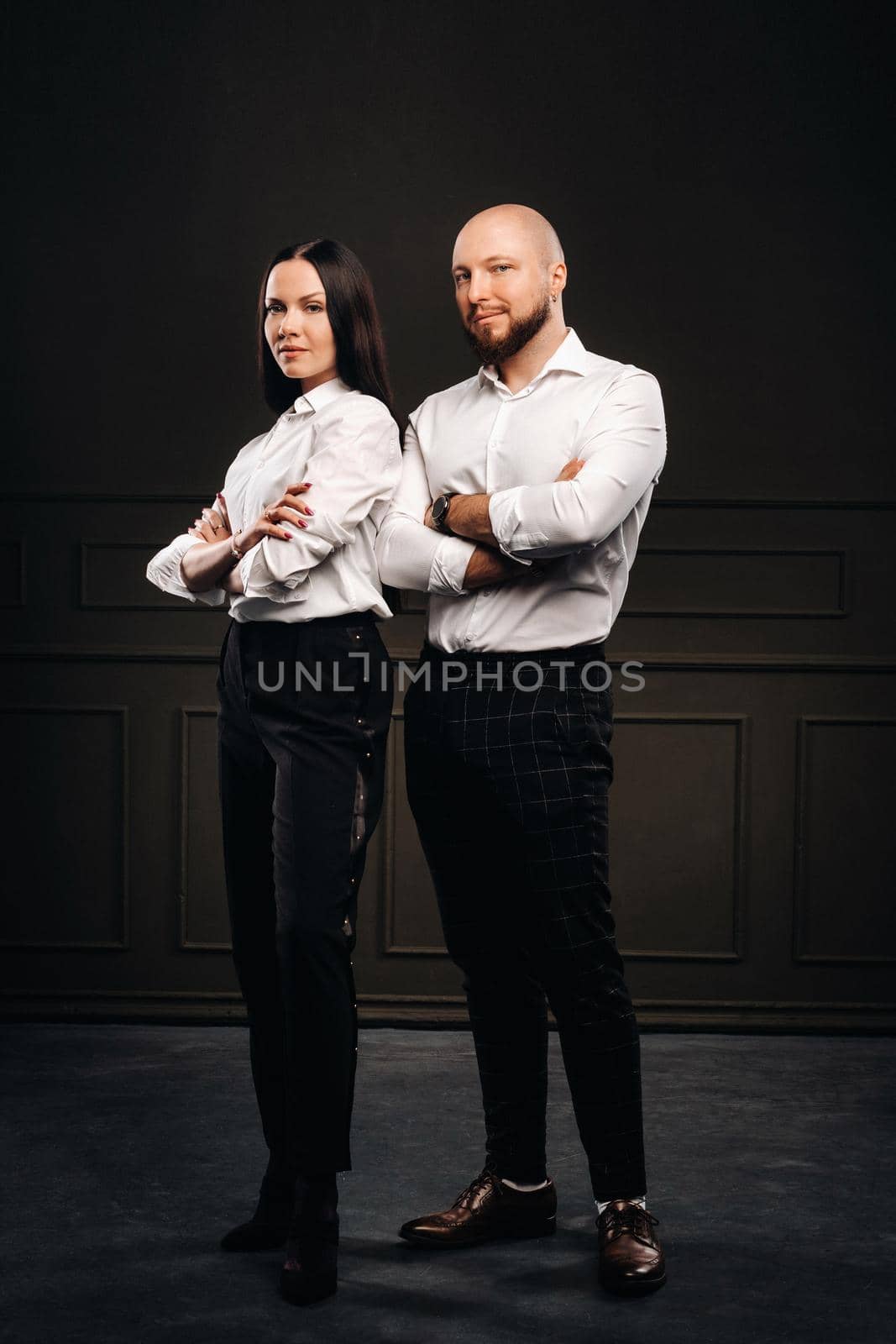 A man and a woman in white shirts on a black background.A couple in love in the studio interior.