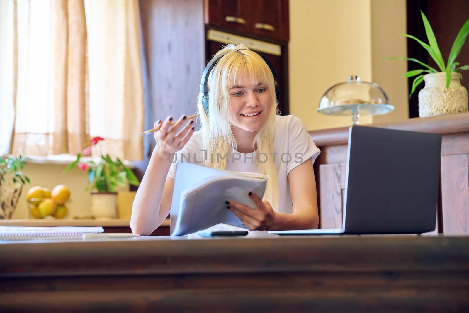 Female student in headphones using a laptop, studying at home by VH-studio