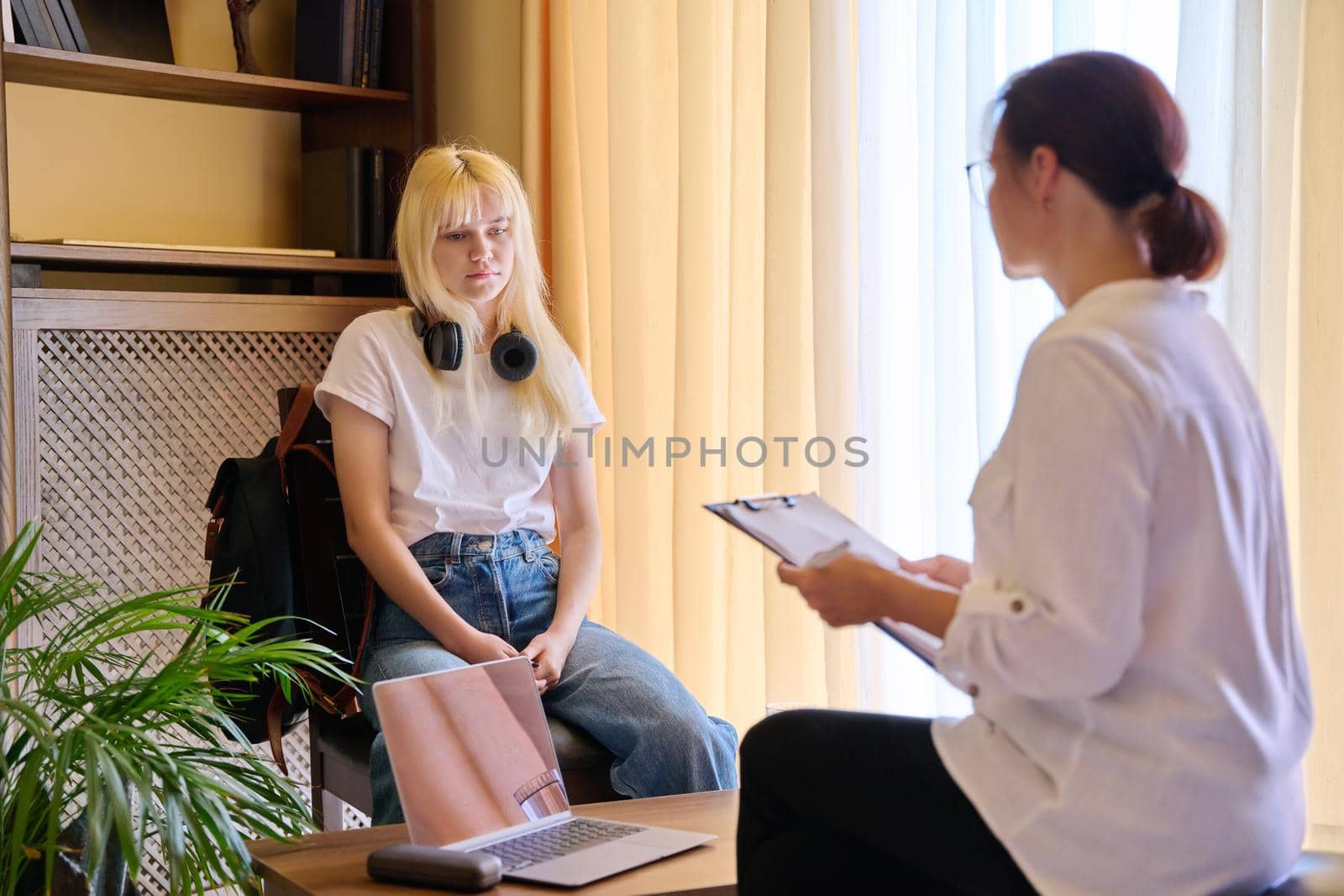 Woman psychologist working with teen girl in office. Visit and counseling of professional mental and social therapist. Psychology, teenager, problem, trauma, mental health of adolescents concept
