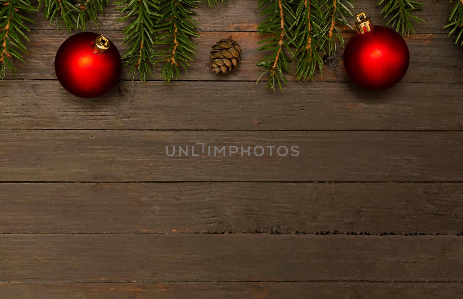 Christmas background.Two red christmas balls,fir cone and fir tree branches on wooden background.