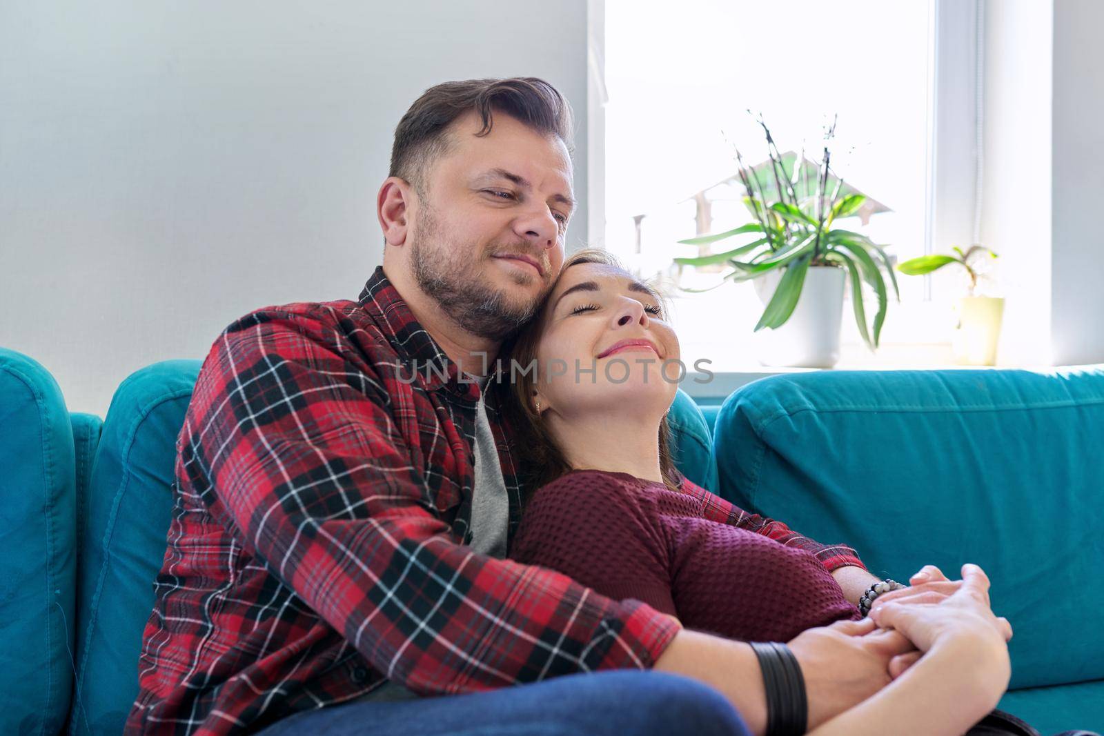 Happy middle-aged couple embracing at home on the couch. Family, happiness, love, relationships, people 40 years old concept