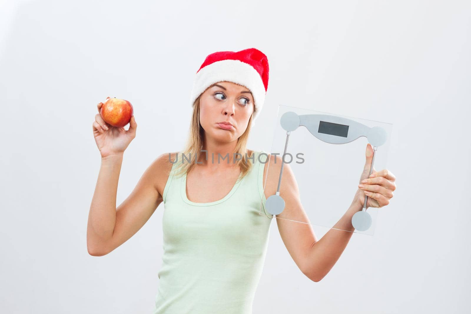 Sad woman in Santa hat holding weight scale and apple by Bazdar