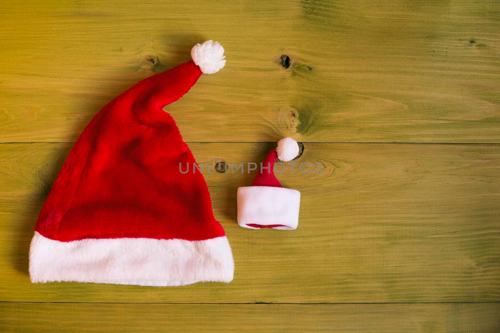 Image of big and small Santa Hat on wooden table.
