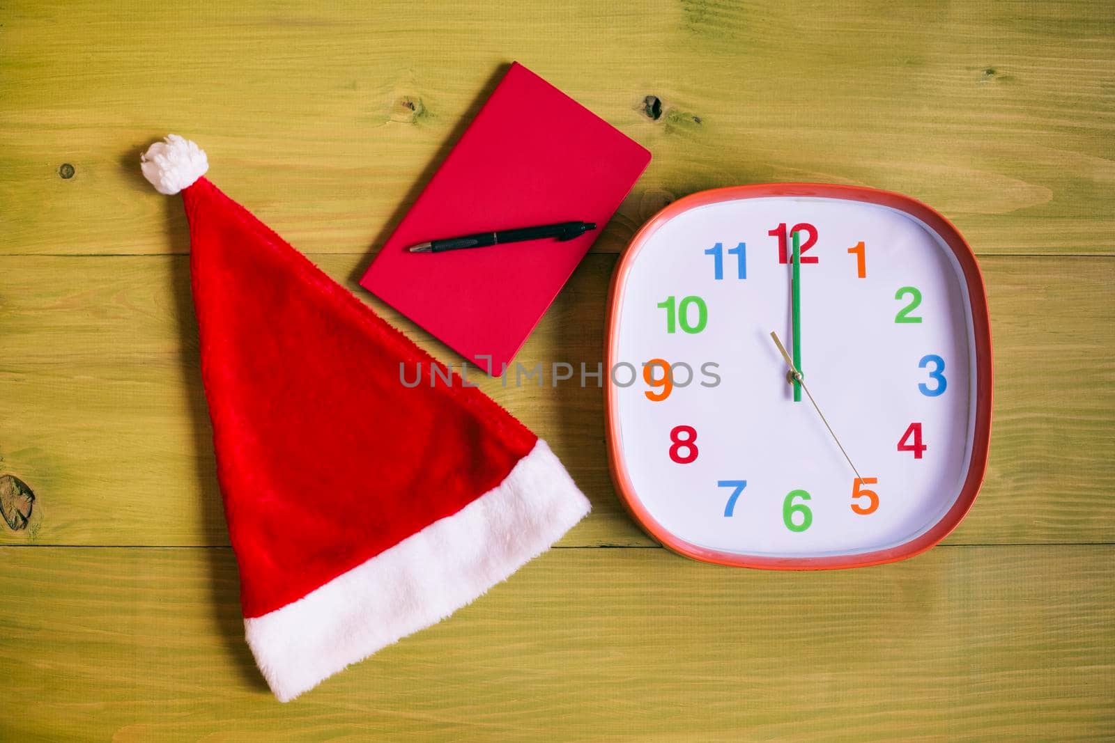Image of Santa Hat,personal organizer and clock showing midnight wooden table.