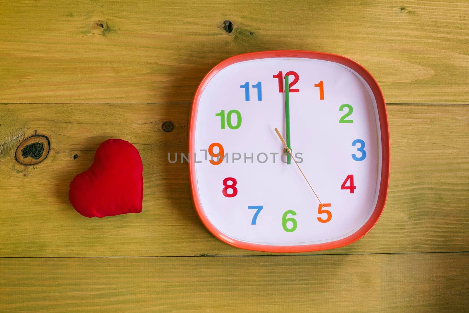 Clock showing midnight and heart on wooden table by Bazdar