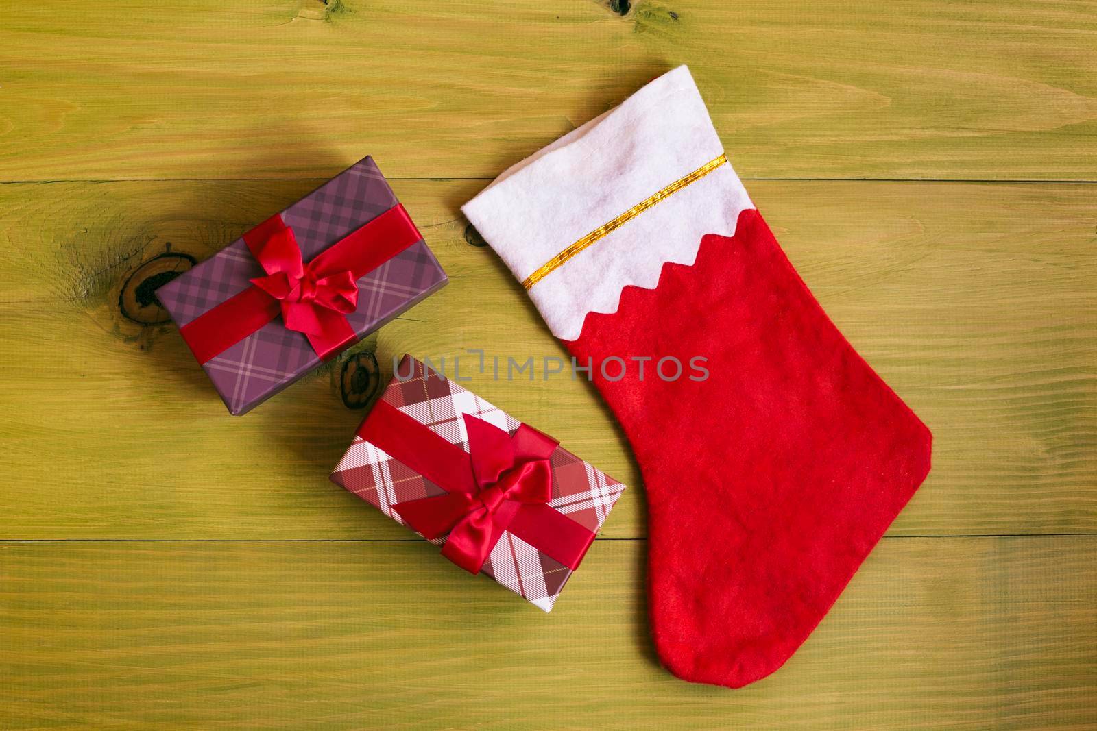 Image of Christmas Stocking and gifts on wooden table.