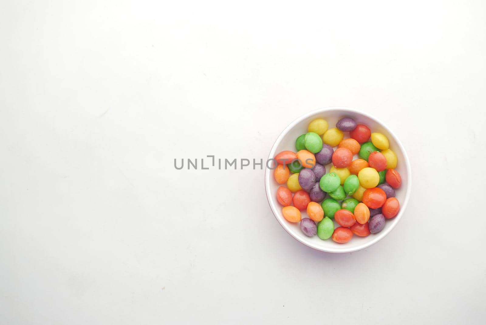 multi-colored sweet candies in a bowl on white background .