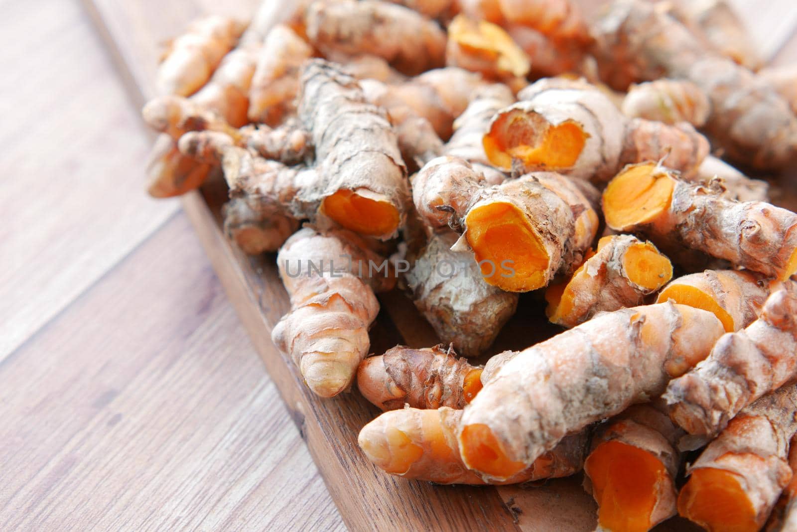 detail shot of turmeric root in a bowl on table .