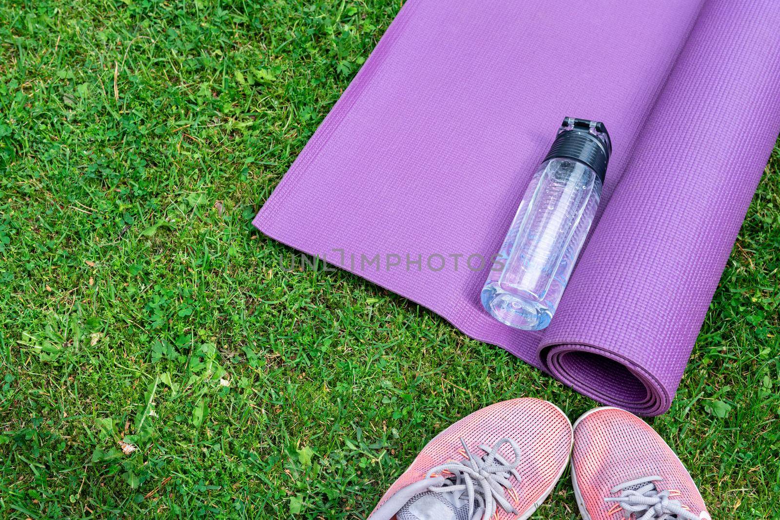 Sneakers, water bottle and a purple fitness mat. Sport concept by anytka