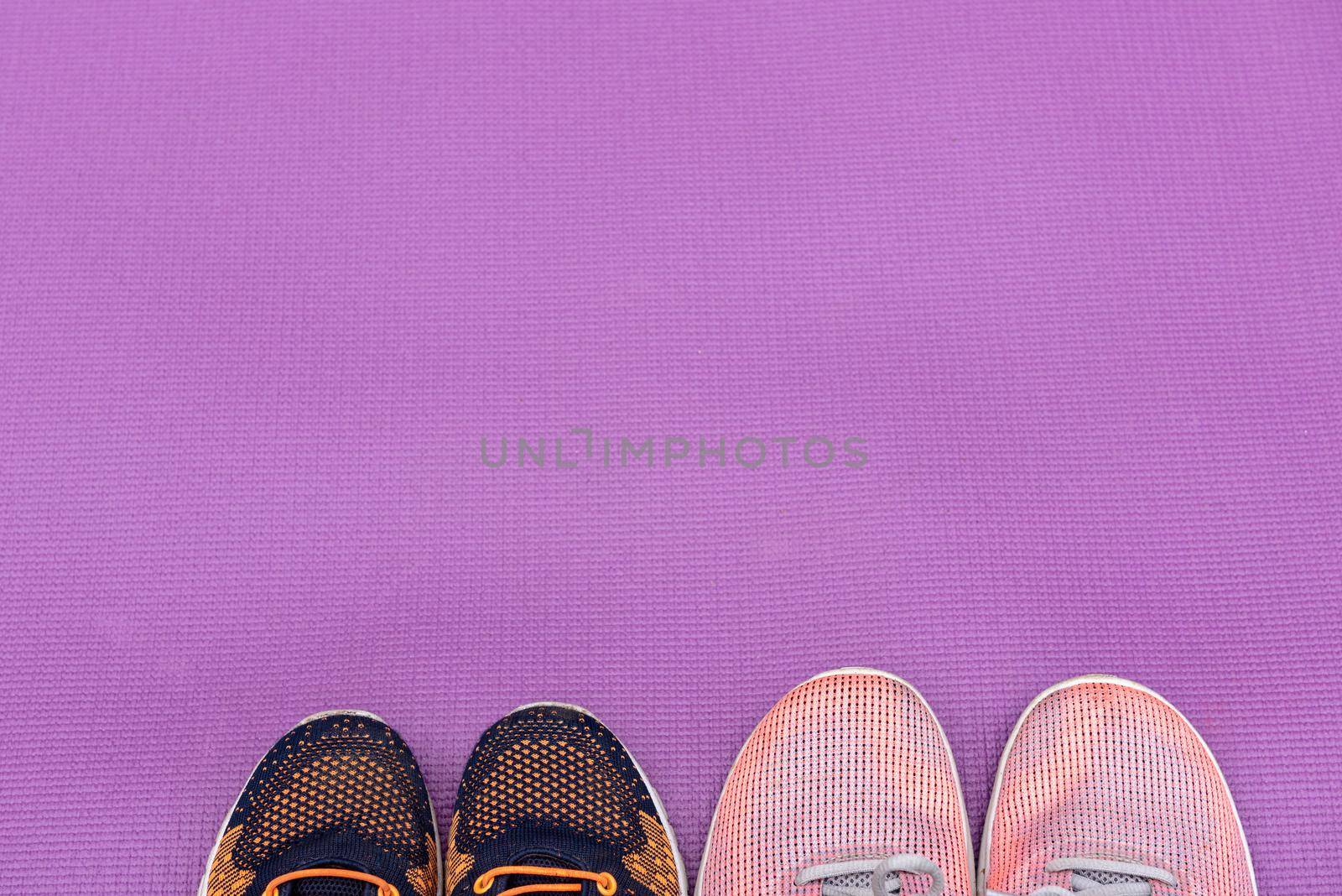Sneakers and a purple fitness mat. Sport concept, top view. Sport concept