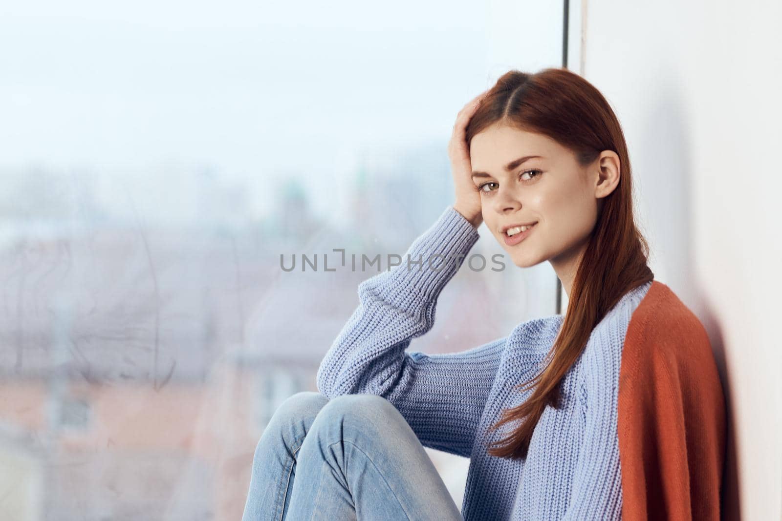 woman with sad expression sits by the window with a plaid. High quality photo