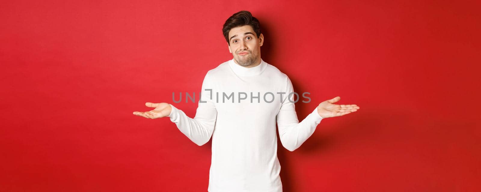 Portrait of clueless handsome guy, shrugging with hands spread sideways, being unaware, dont know anything, standing over red background by Benzoix