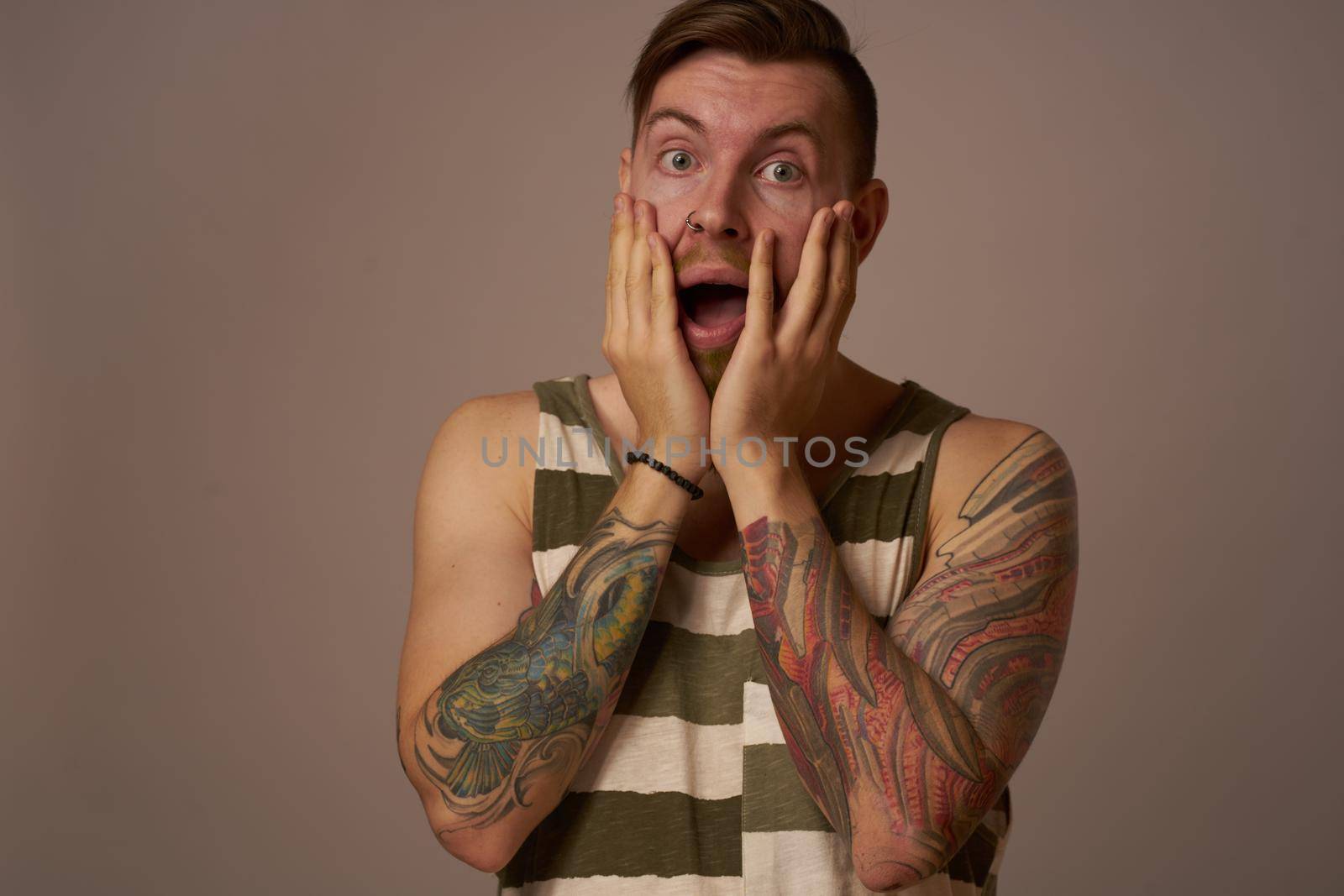 handsome man with tattoos on his arms fashionable hairstyle emotions. High quality photo