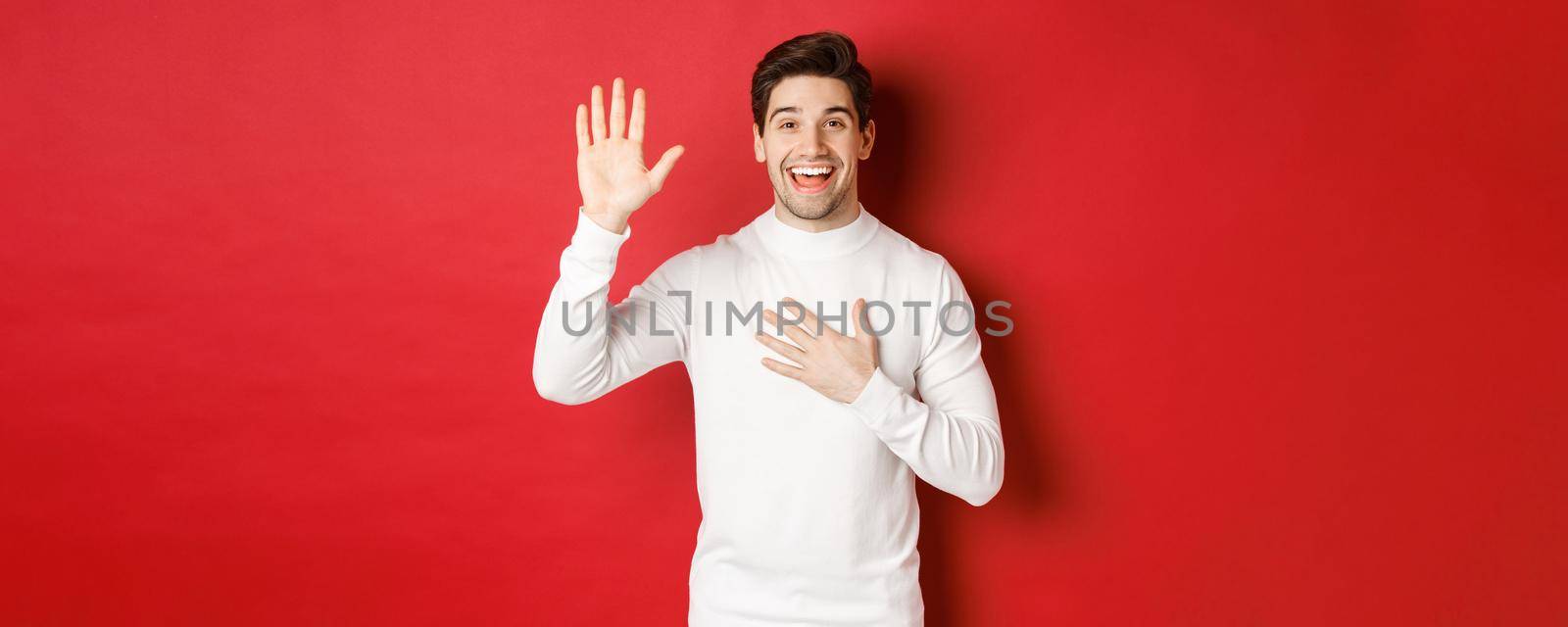 Portrait of honest smiling man in white sweater, making a promise, swearing to tell truth, standing against red background by Benzoix