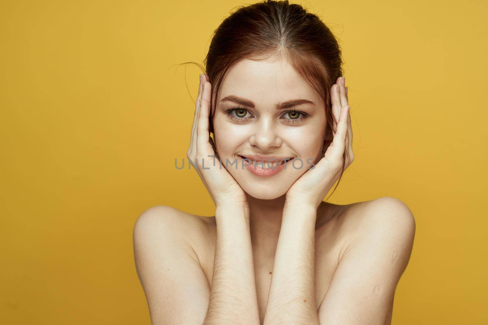 pretty woman naked shoulders and posing clear skin yellow background. High quality photo