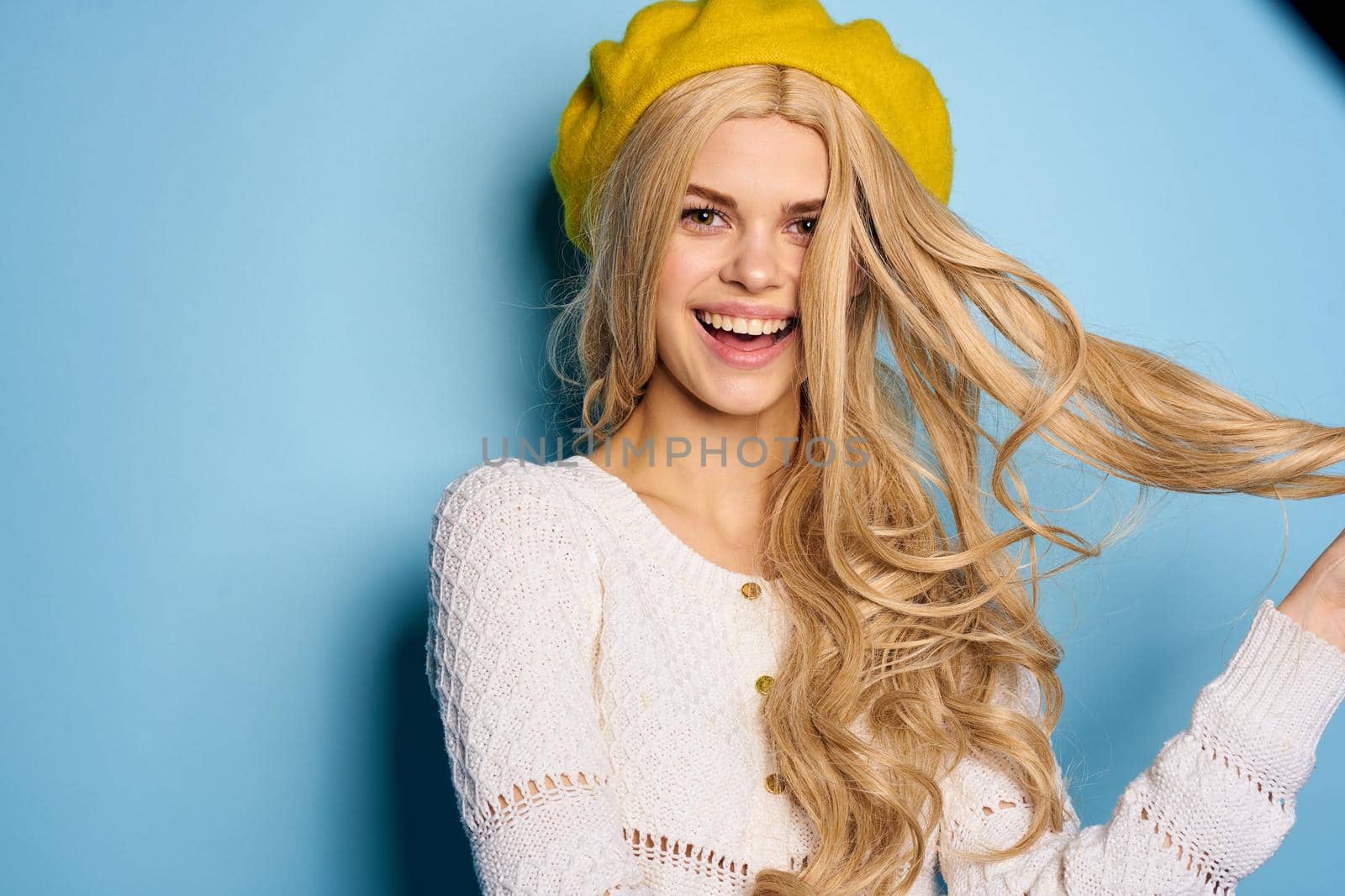 woman in yellow hat posing glamor blue background. High quality photo