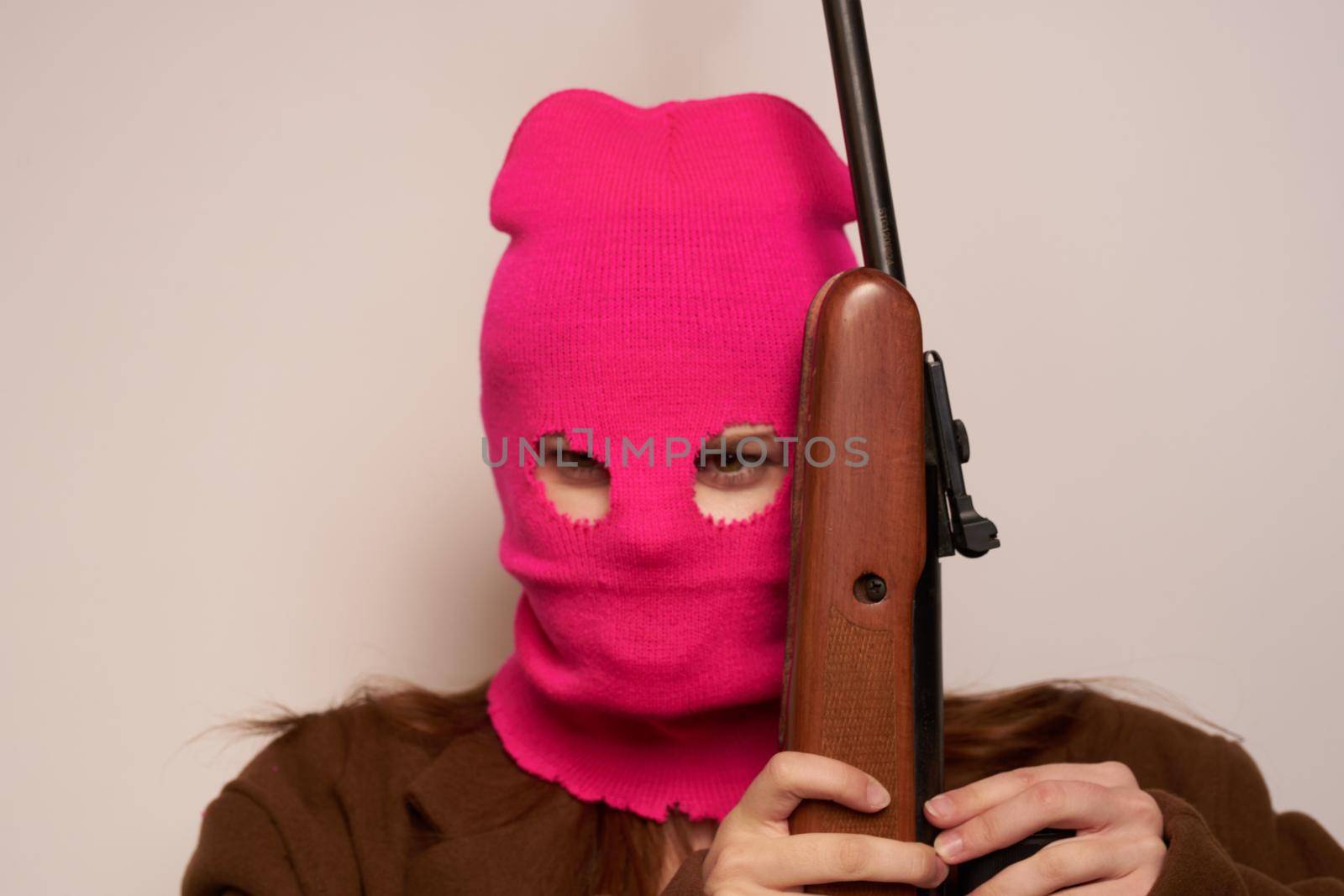 female shooter with a gun in hand Lifestyle beige background. High quality photo