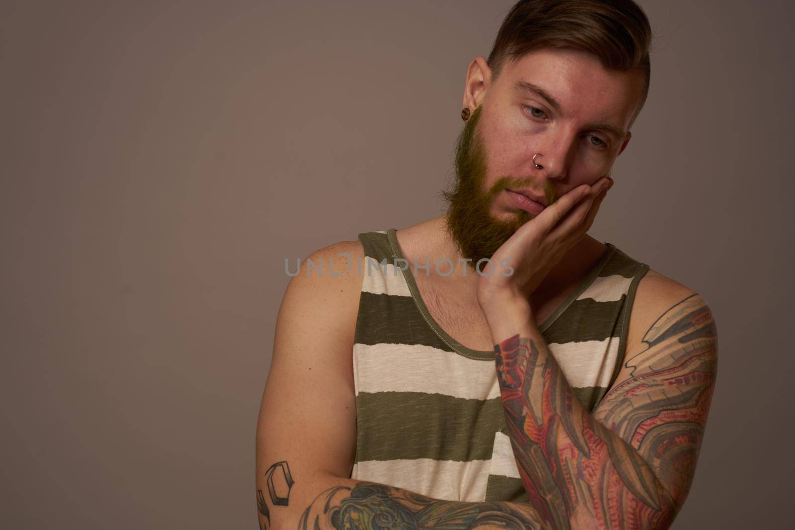 fashionable man with tattoos on his arms stylish hairstyle self-confidence studio. High quality photo