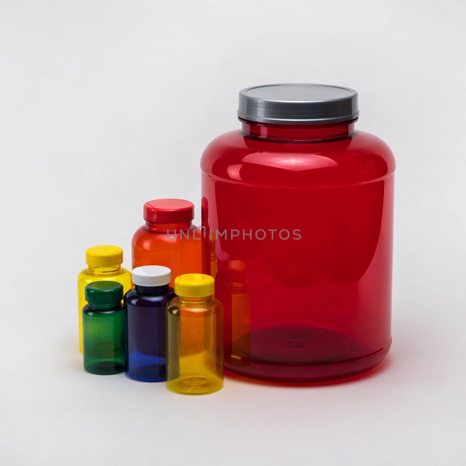 Multi colored transparent plastic pill jars on a white background. Isolated