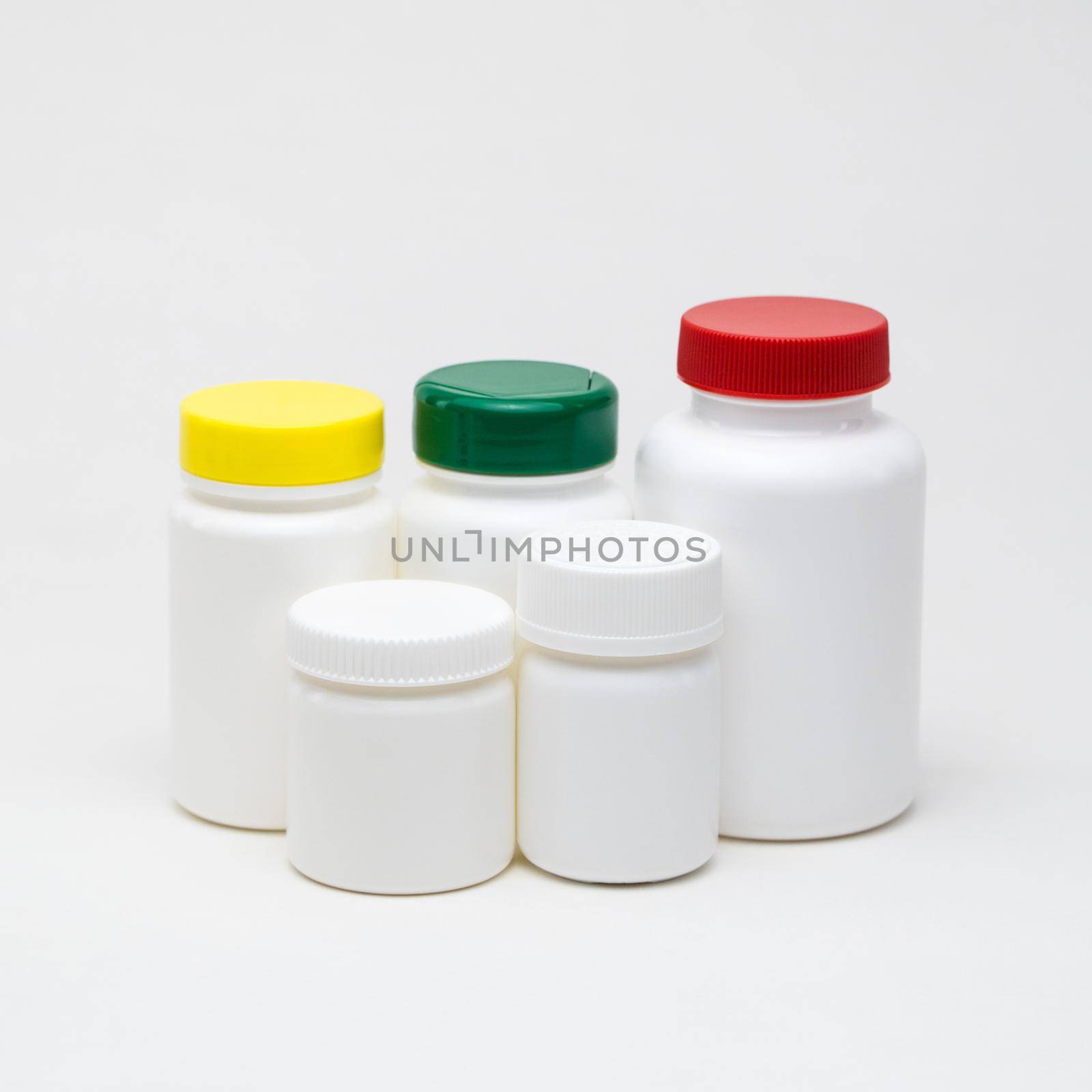 White plastic pill jars on a white background. Multi colored lids. Isolated