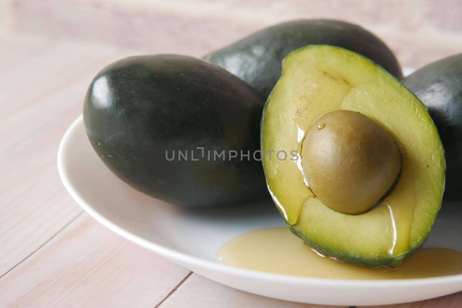 honey pouring on a slice of avocado on wooden table .