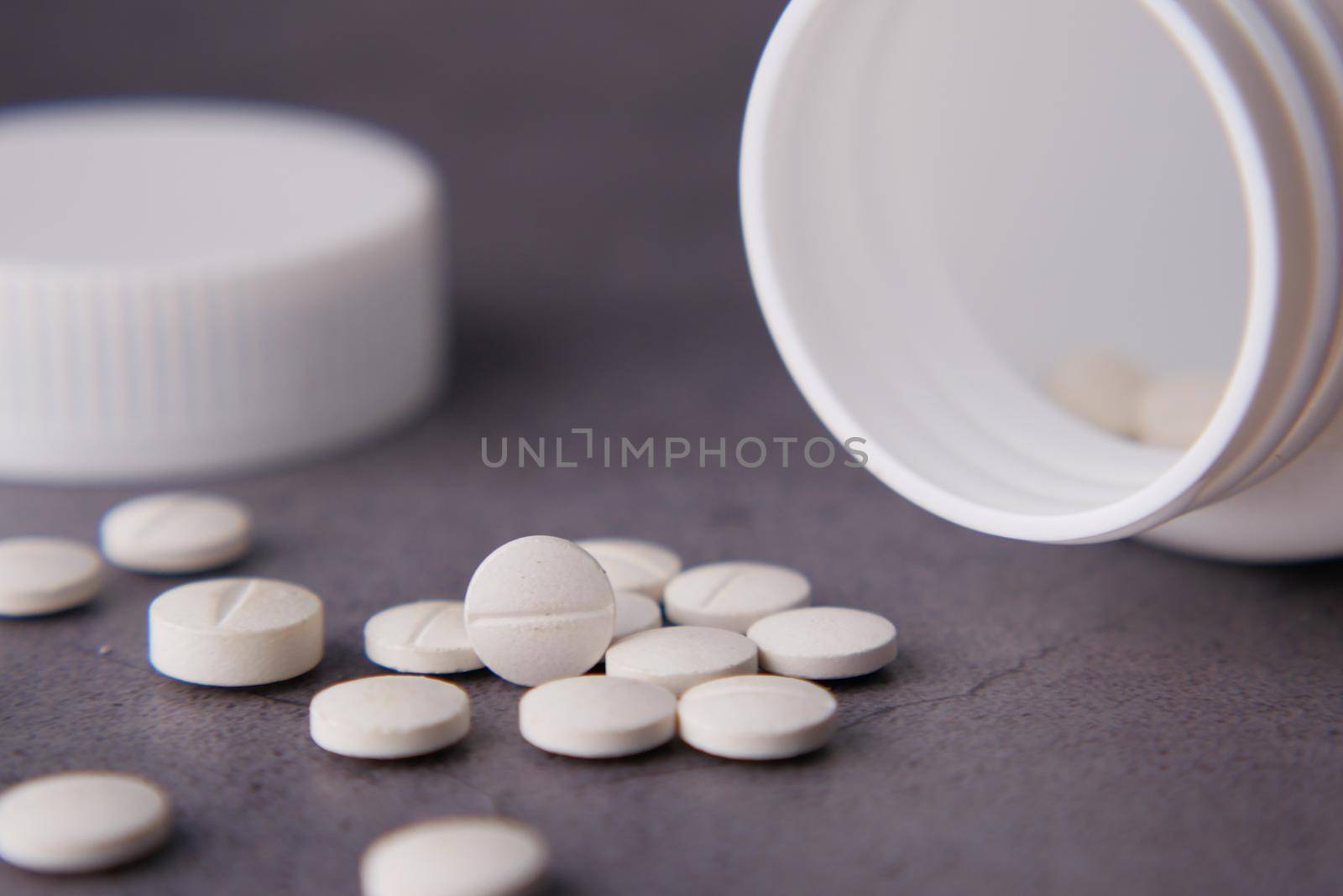 white color medical pills spilling on black background .