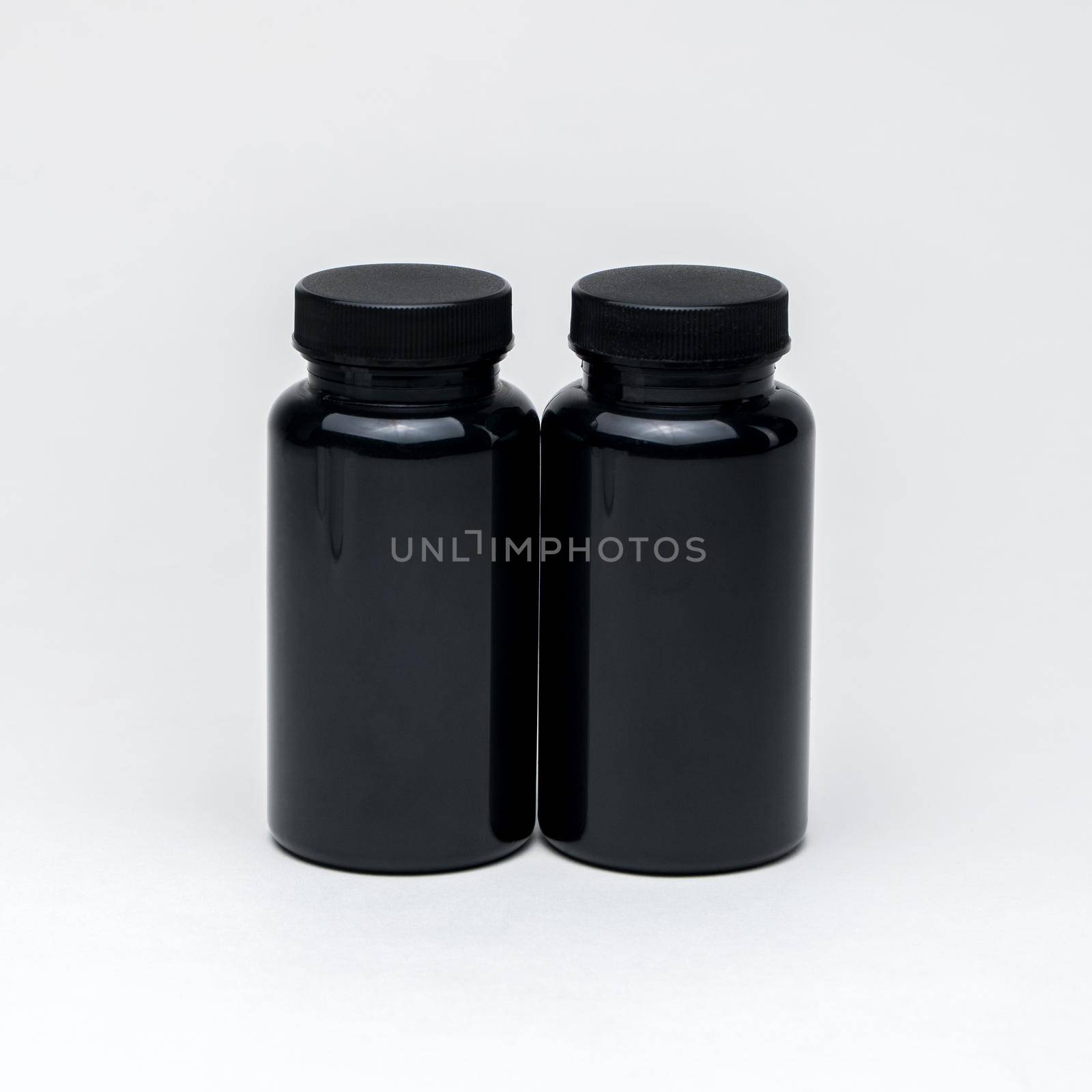 Black plastic pill jars on a white background. Isolated