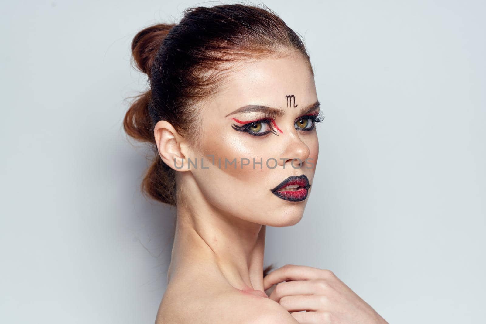 beautiful woman posing scorpio sign on forehead cosmetics light background. High quality photo