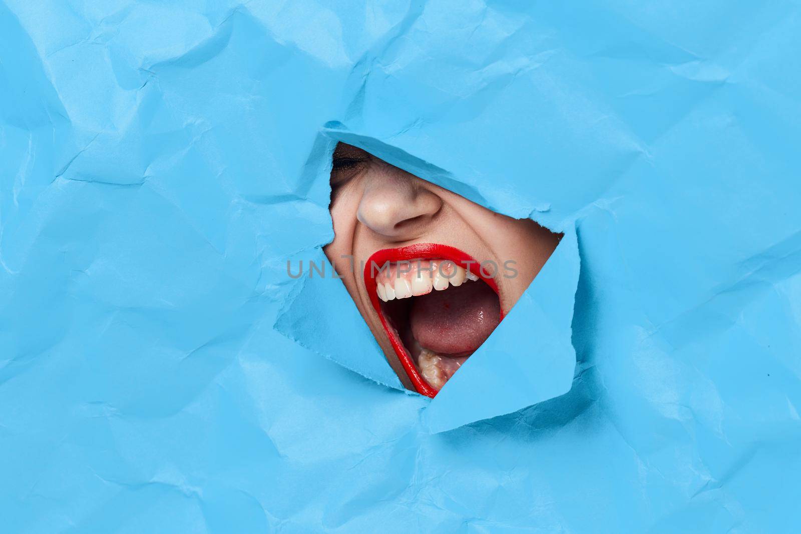 woman's face breaks through blue mockup close-up. High quality photo