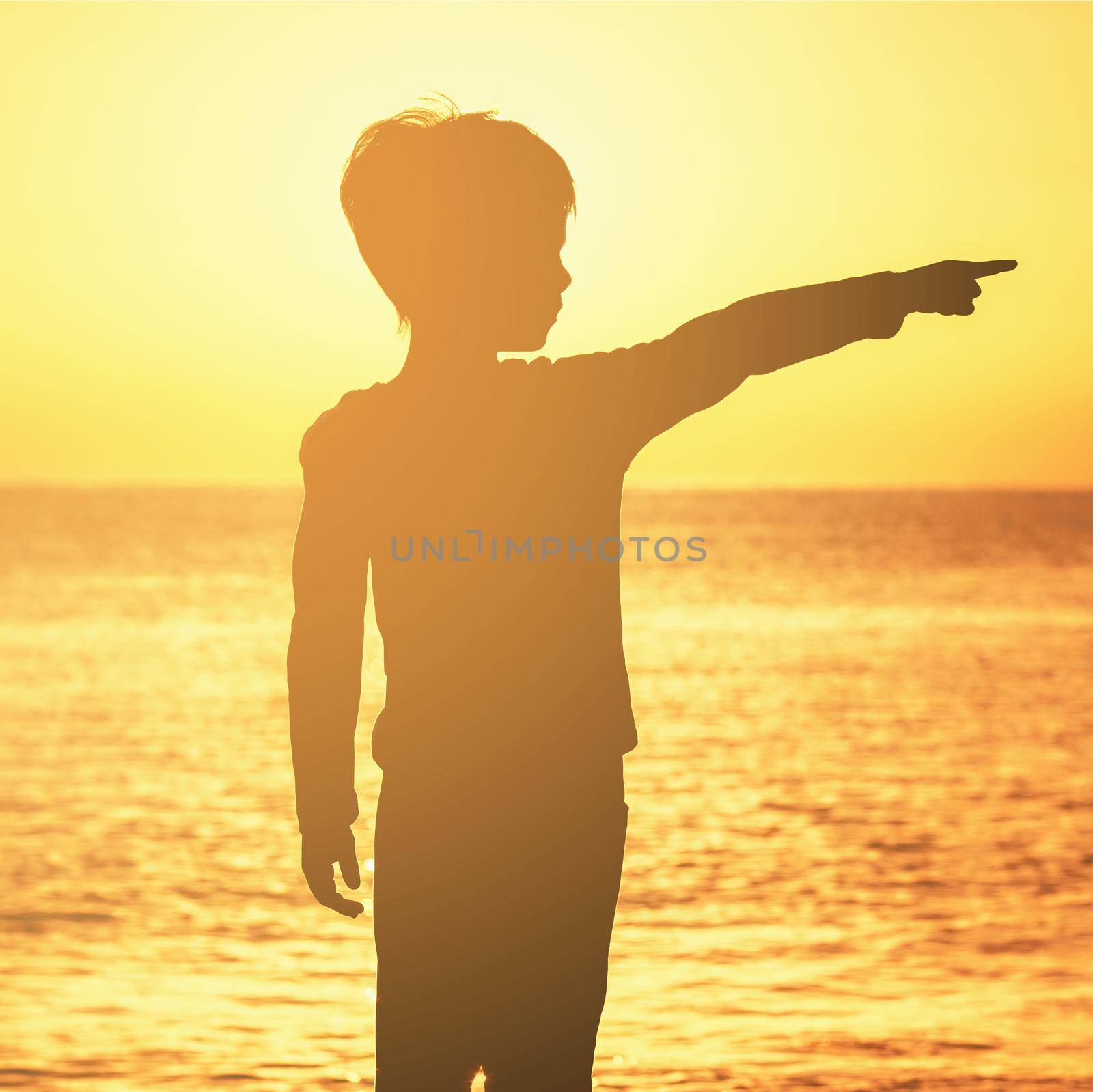 contour of a boy with thumbs raised at sunrise sunset on the seashore of the ocean orange sky orange sea ocean boy shows his index finger to the side by AntonIlchanka