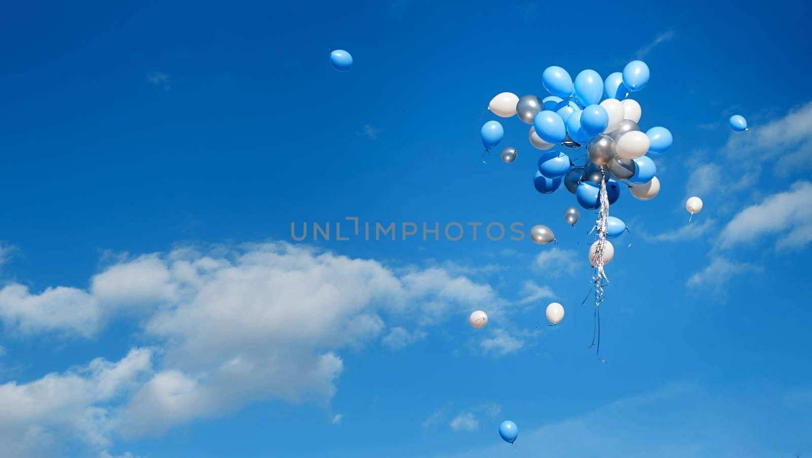 White and blue balloons were released and fly high in the blue sky. High quality photo