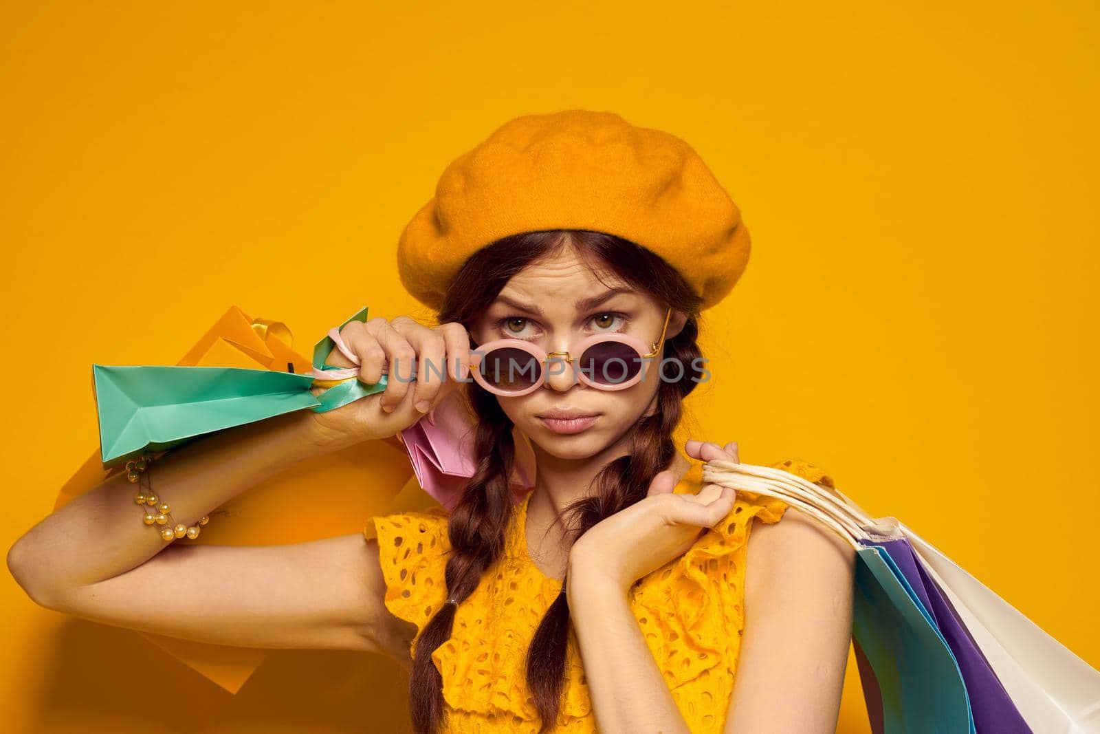 pretty woman with multicolored bags posing yellow background. High quality photo