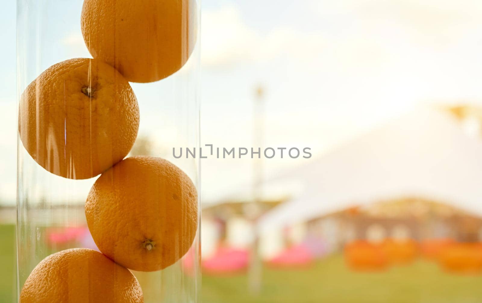 Three organic juicy sweet healthy oranges, close-up, in a crystal vase on a colorful nature background. High quality photo