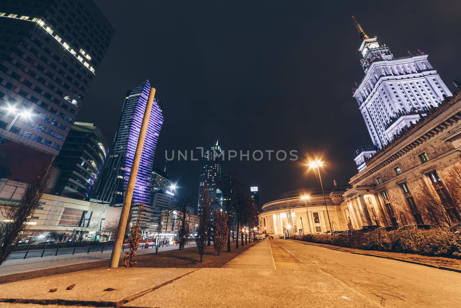 Warsaw at night in the city center with modern and ancient building on the background.