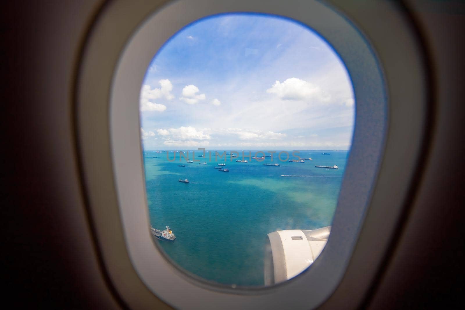 beautiful view from the window of the plane to the sea and cargo ships. carefree view from porthole landing airplane