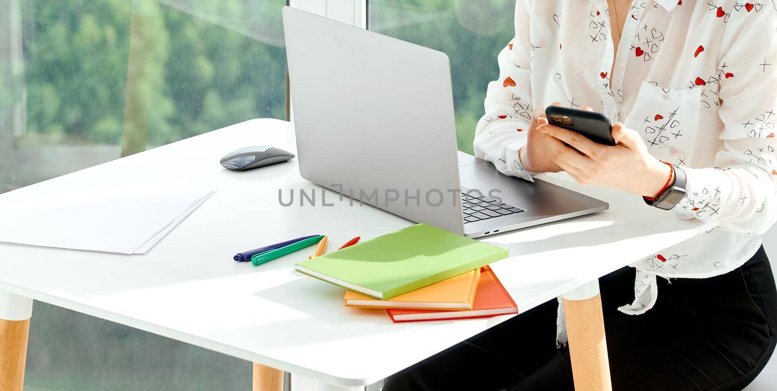 Woman works remotely at a table with laptop and notepads on her balcony . High quality photo