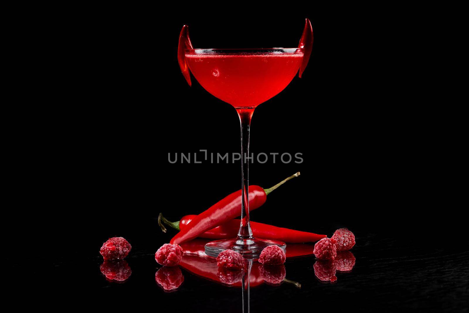 cocktail on a black background with red hot pepper and raspberries . High quality photo
