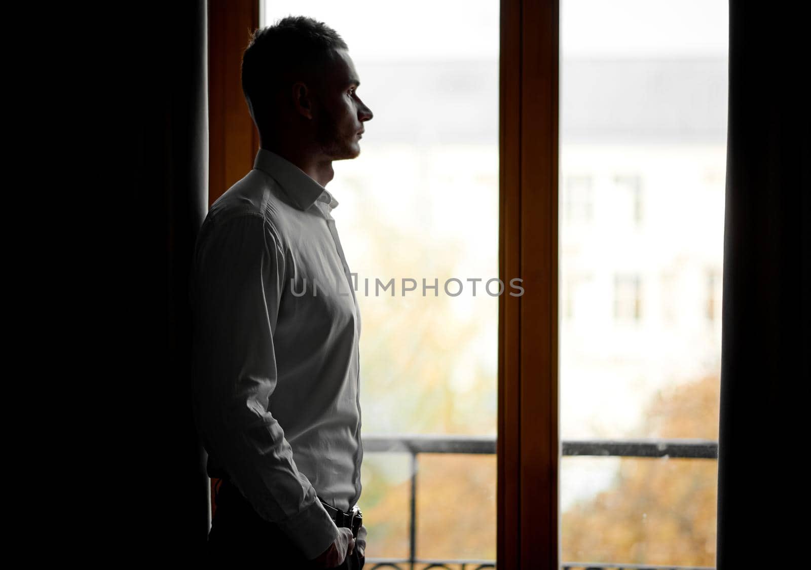 guy in a white shirt looks at the city through the window. High quality photo