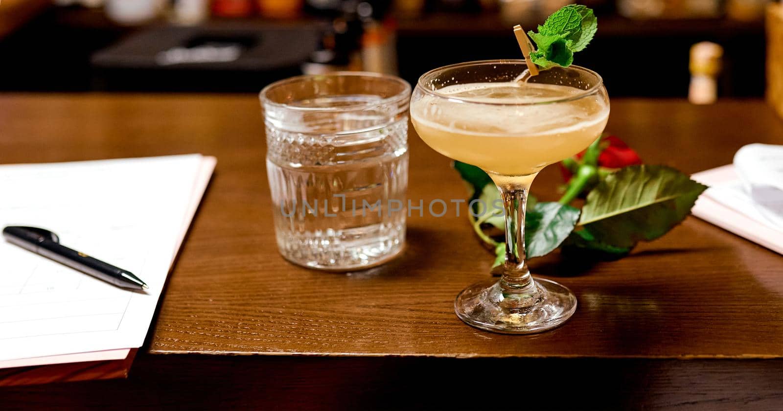 cocktail in a glass of yellow on a wooden table with sheets of paper for evaluation. High quality photo