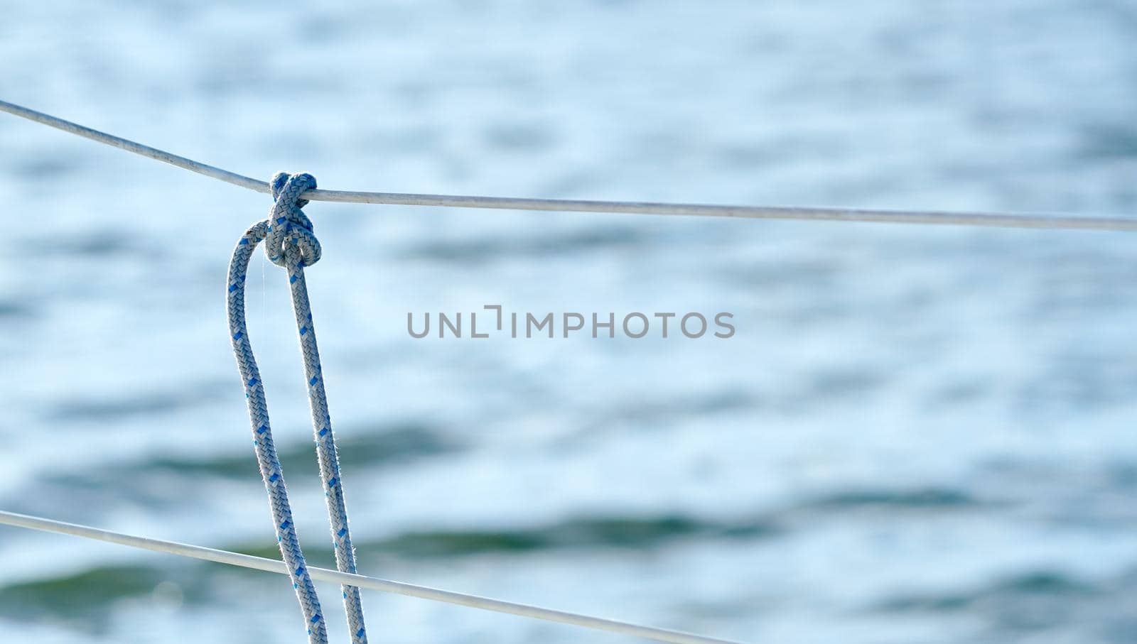 Knot on the fence of the yacht board against the background of the ocean sea water. High quality photo