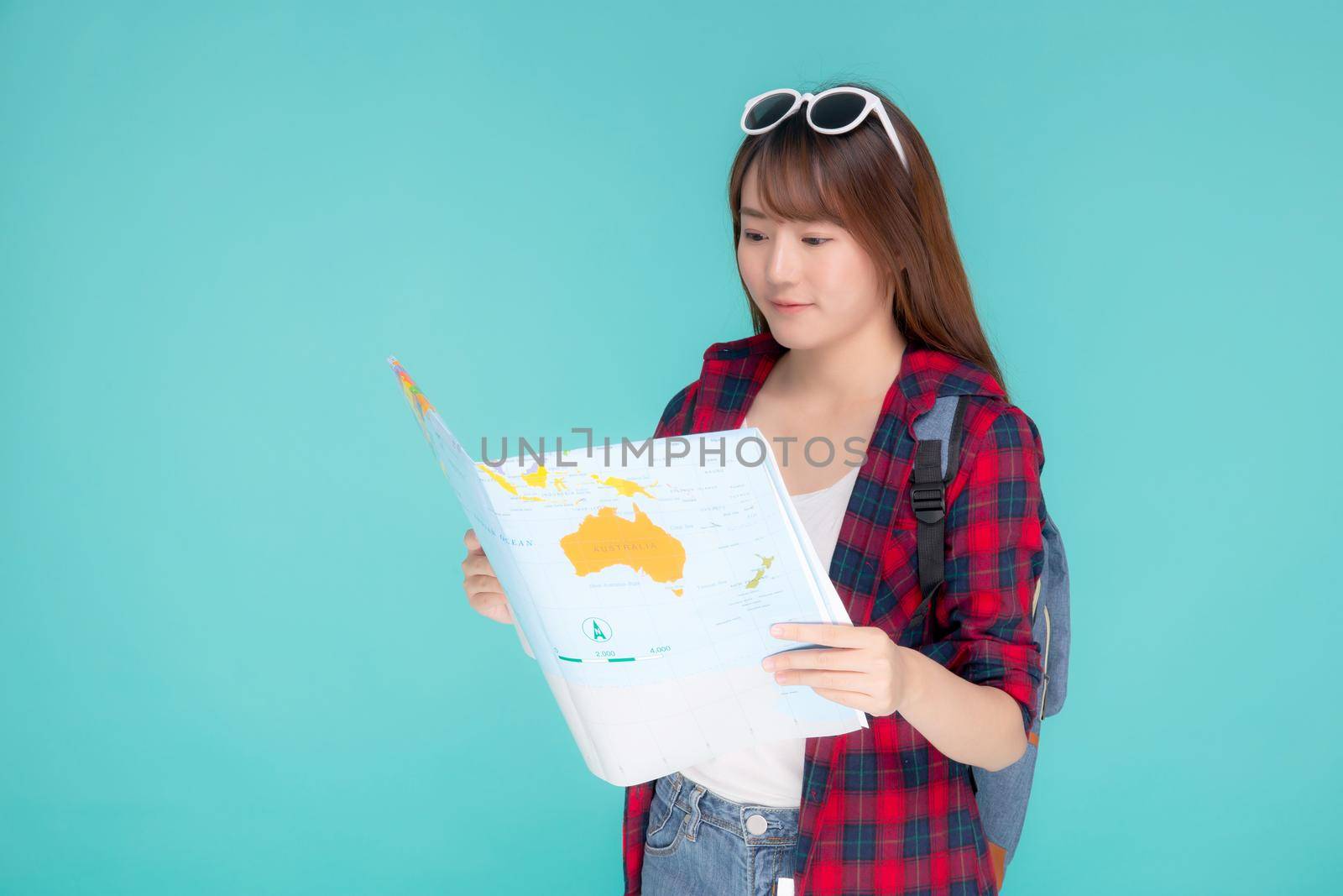 Beautiful happy young asian woman travel holding and looking a paper map isolated on blue background, asia girl search journey with direction in vacation trip with cheerful for leisure. by nnudoo