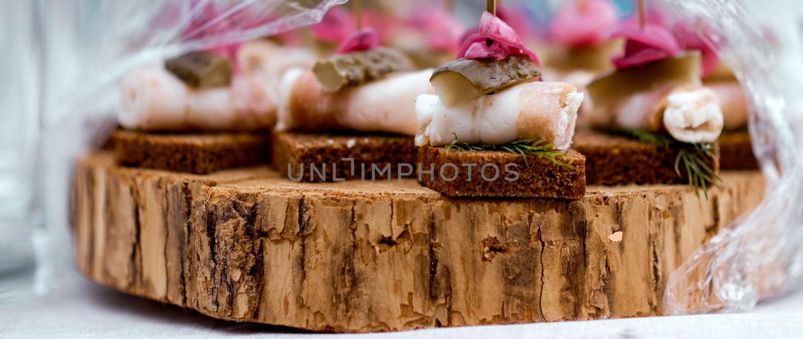 Canape of lard, bread, cucumber on a piece of wood under the film . High quality photo