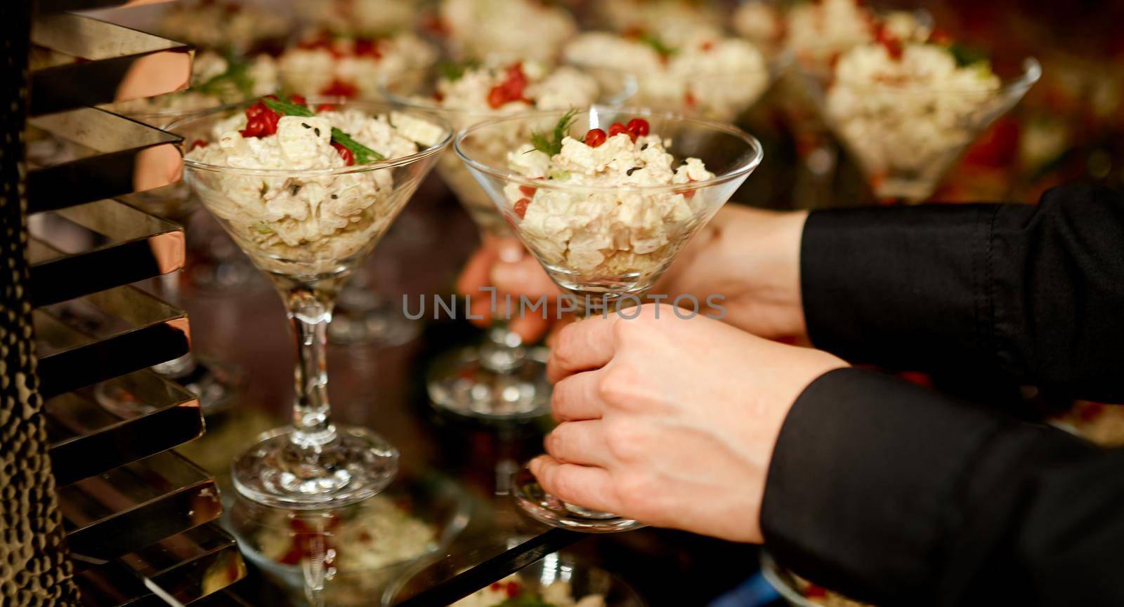 Waiter puts on a glass shelf salad with mayonnaise in glasses for Martini . High quality photo