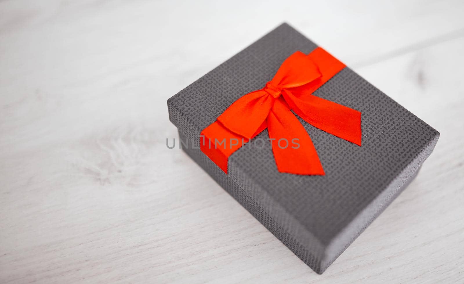 Gift box present isolated with clipping path with red bow satin on pine wood background. by AntonIlchanka