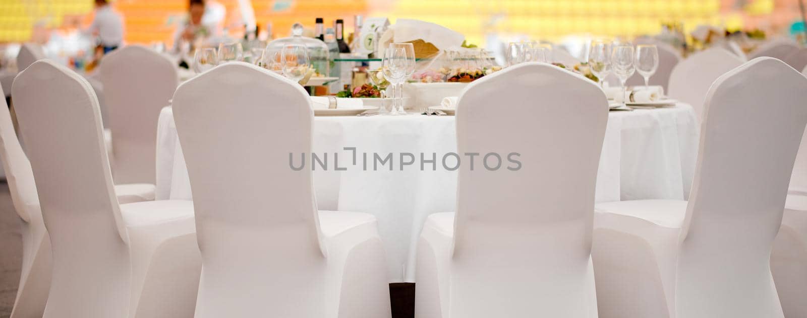 Served a full meal table with chairs in white covers ready to be received . High quality photo
