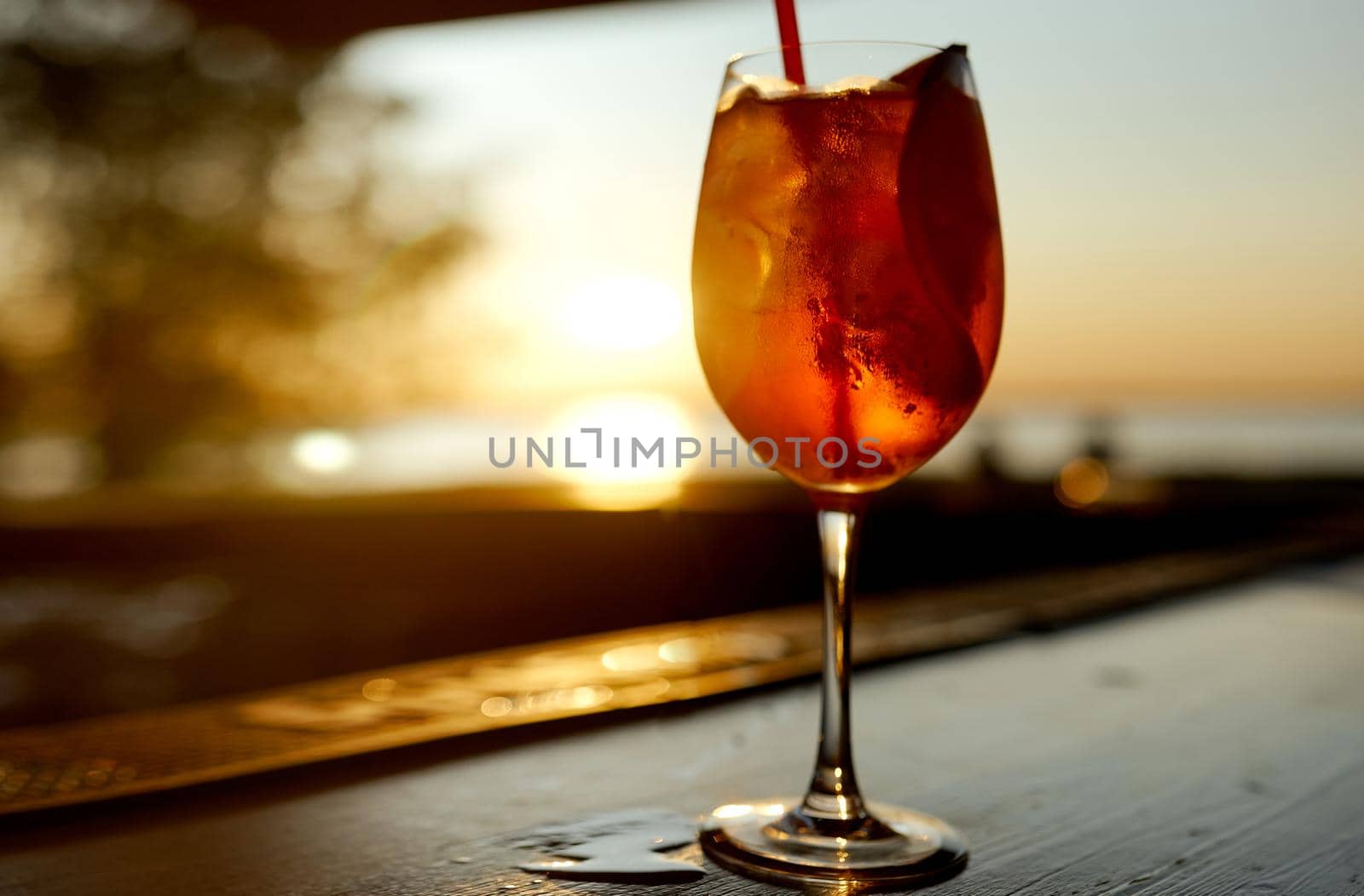 Cocktail glass with a tube on the background of the sea and sunset. High quality photo