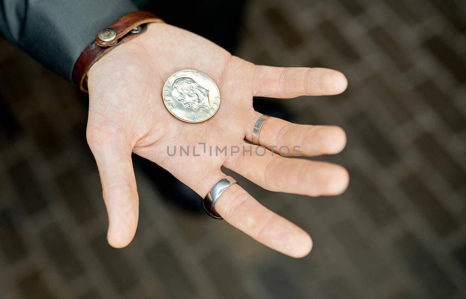 Magician holds the coin before focusing on the open palm against the background of the tile . High quality photo