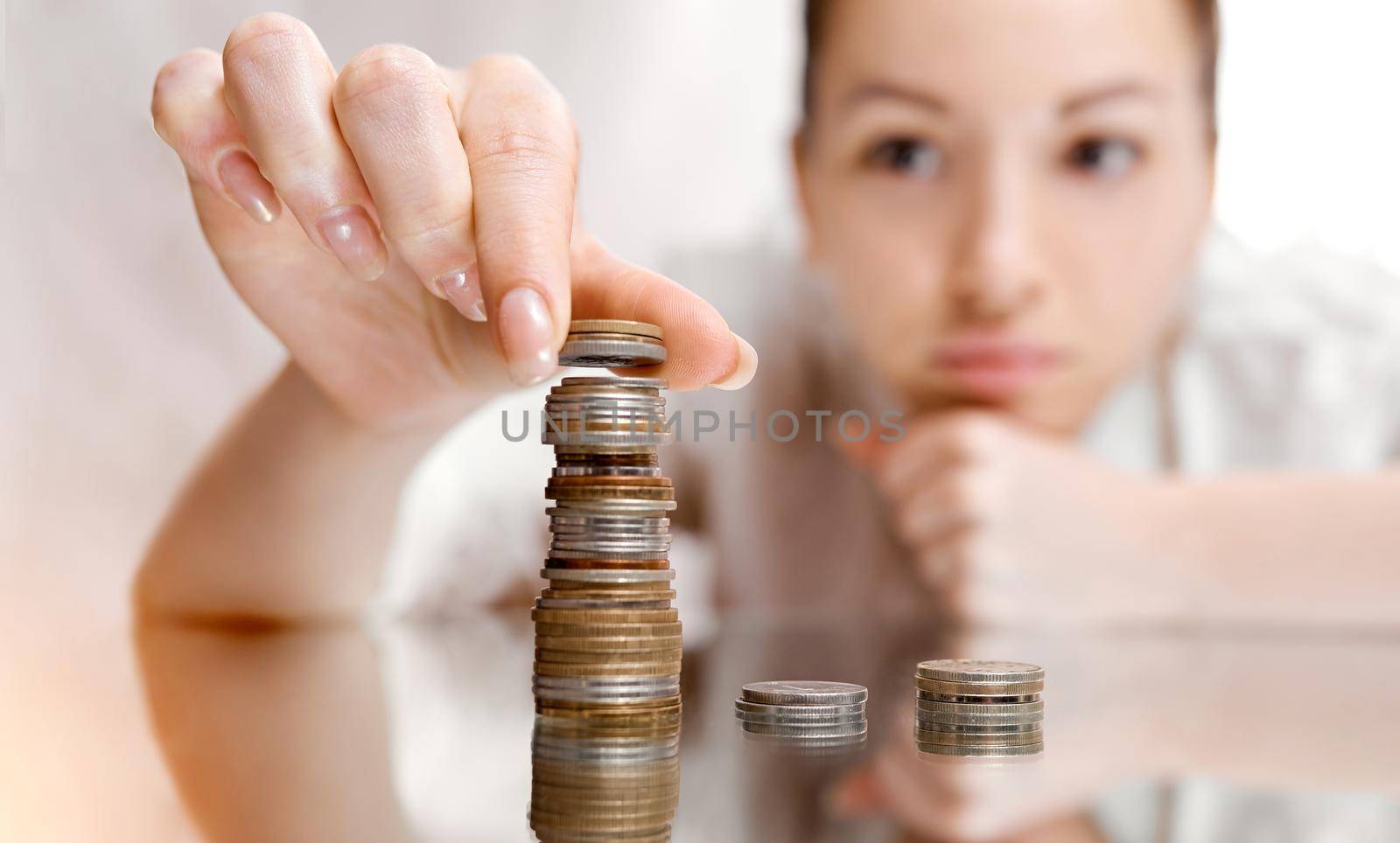 A thoughtful woman shifts coins from the pile to the pile. There's a coin tower. . High quality photo